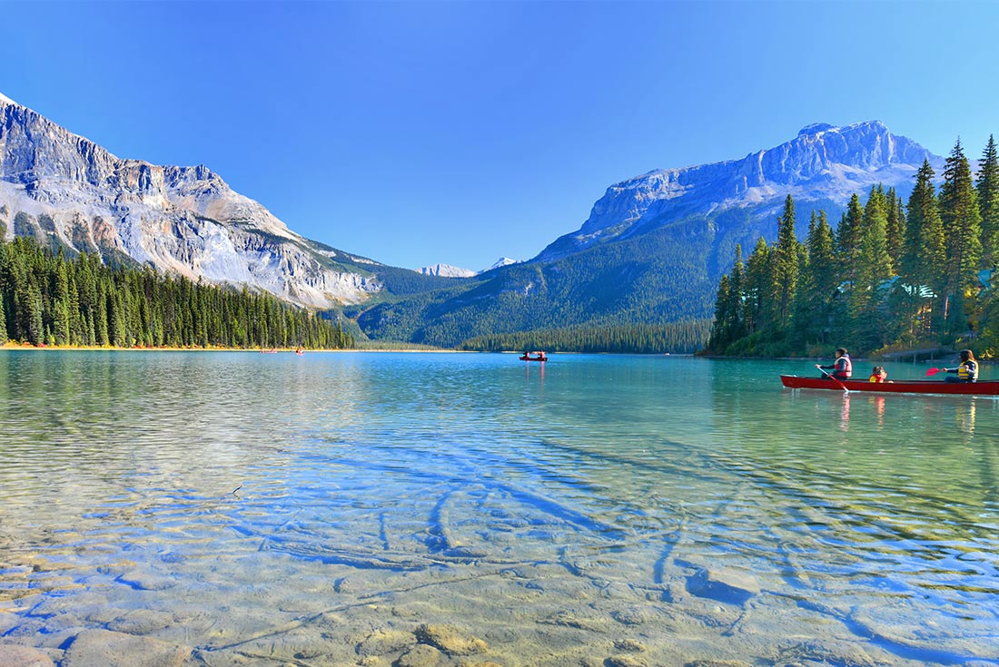 People canoeing across crystal clear waters in Emerald Lake, Yoho National Park