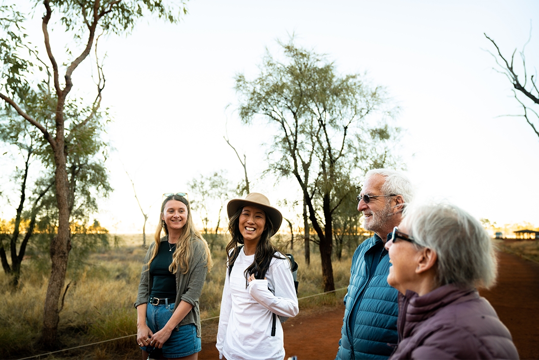 Group of travellers laugh against the Red Centre desert backdrop