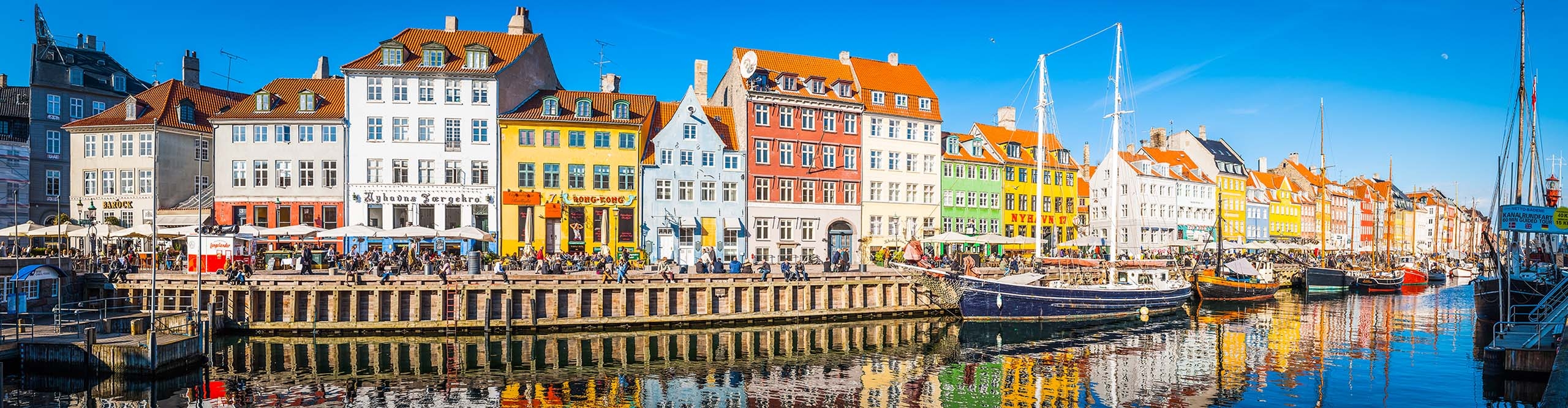 crowds enjoying sunshine at restaurants and bars along the waterfront of Copenhagen Denmark