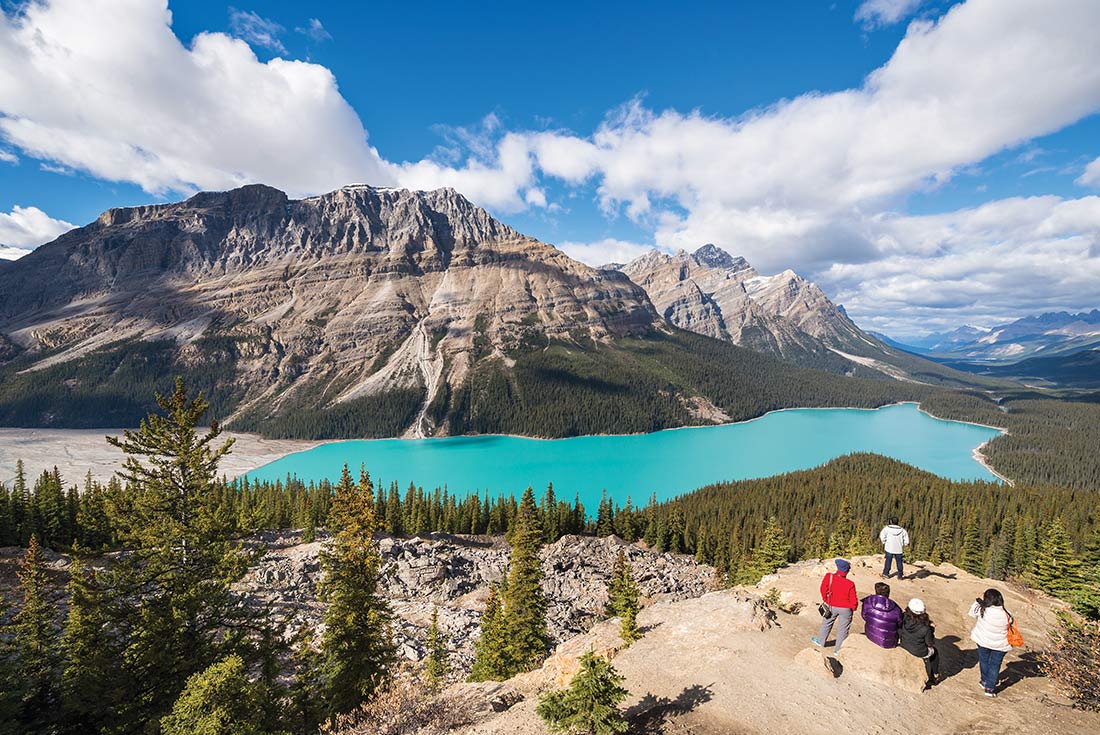 Group of travellers admiring Peyto lake and mountains in Calgary, Alberta 