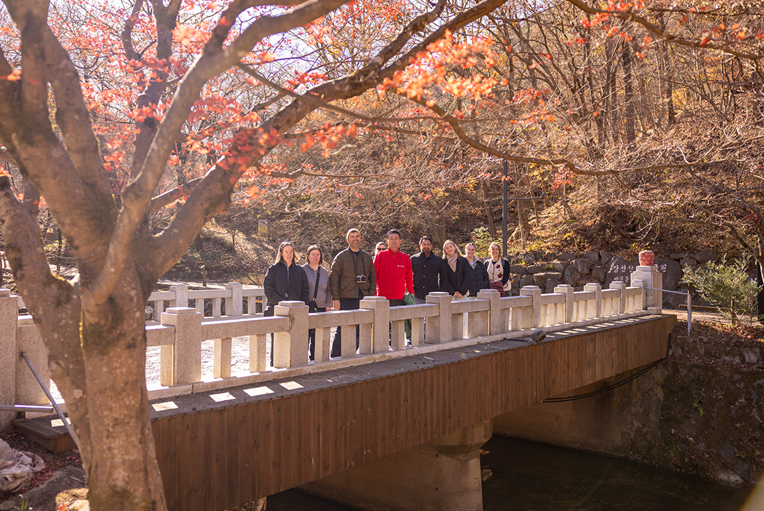 Group stopping to pose for a photo on a bridge on a walk to a waterfall at Mount Gangcheon, South Korea