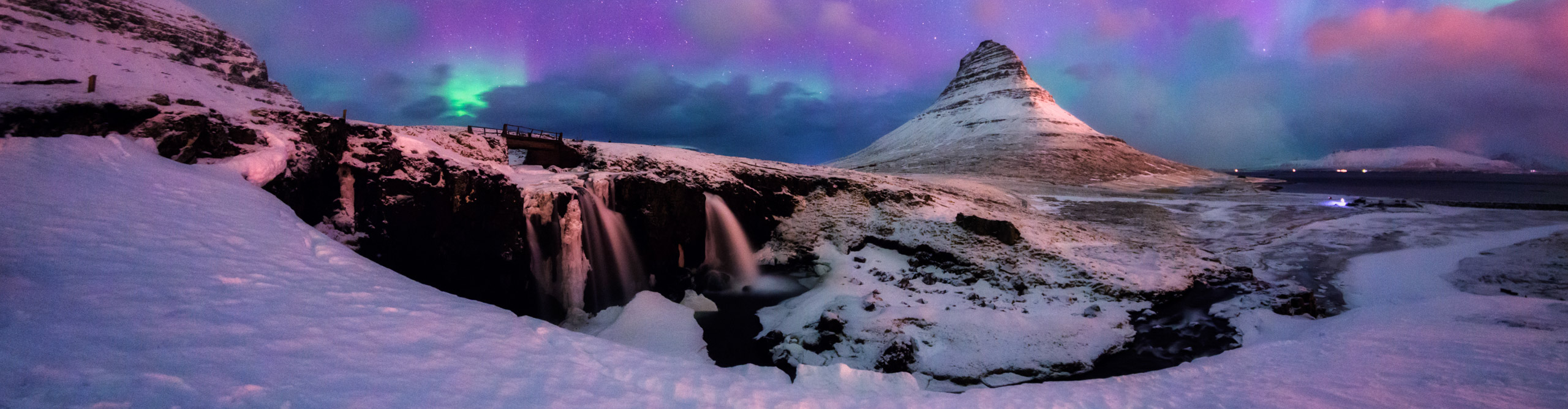 Pink green and blue Northern Lights over the snow-covered  Kirkjufell Mountain,  Iceland.