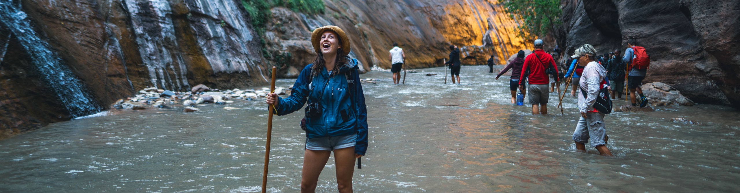 Woman smiling while hiking through the river in the canyon in Zion National Park, Utah, USA