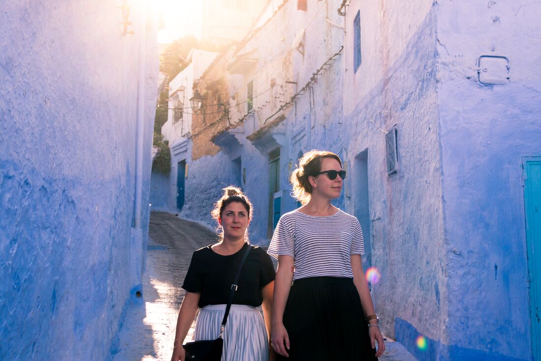 Two Intrepid travellers walk through the blue-lined streets of Chefchaouen, Morocco