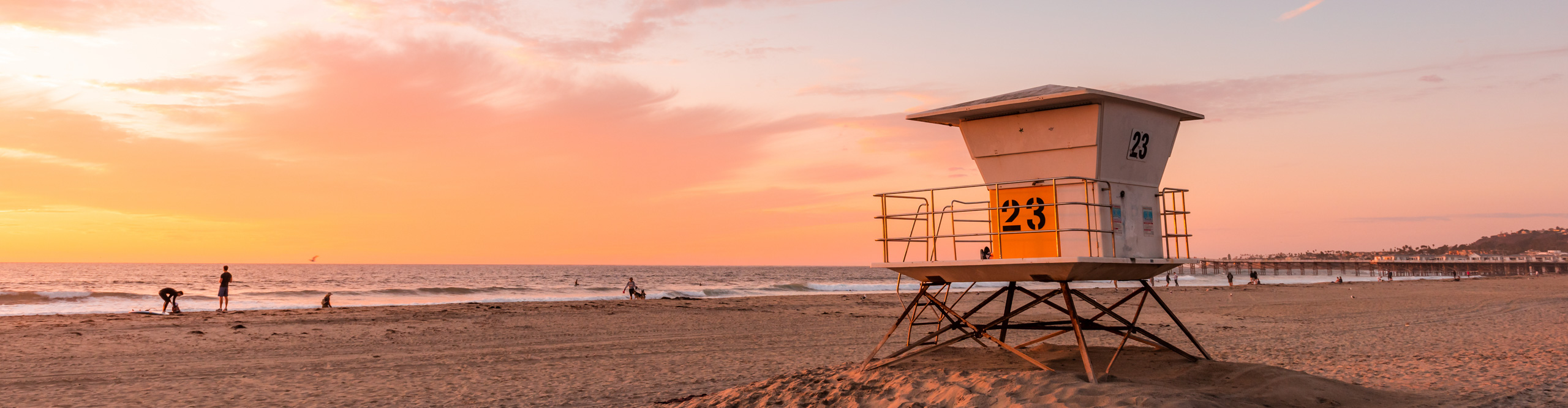 Lifeguard Tower on the beach at sunset in California, with pink skies and clouds and waves crashing