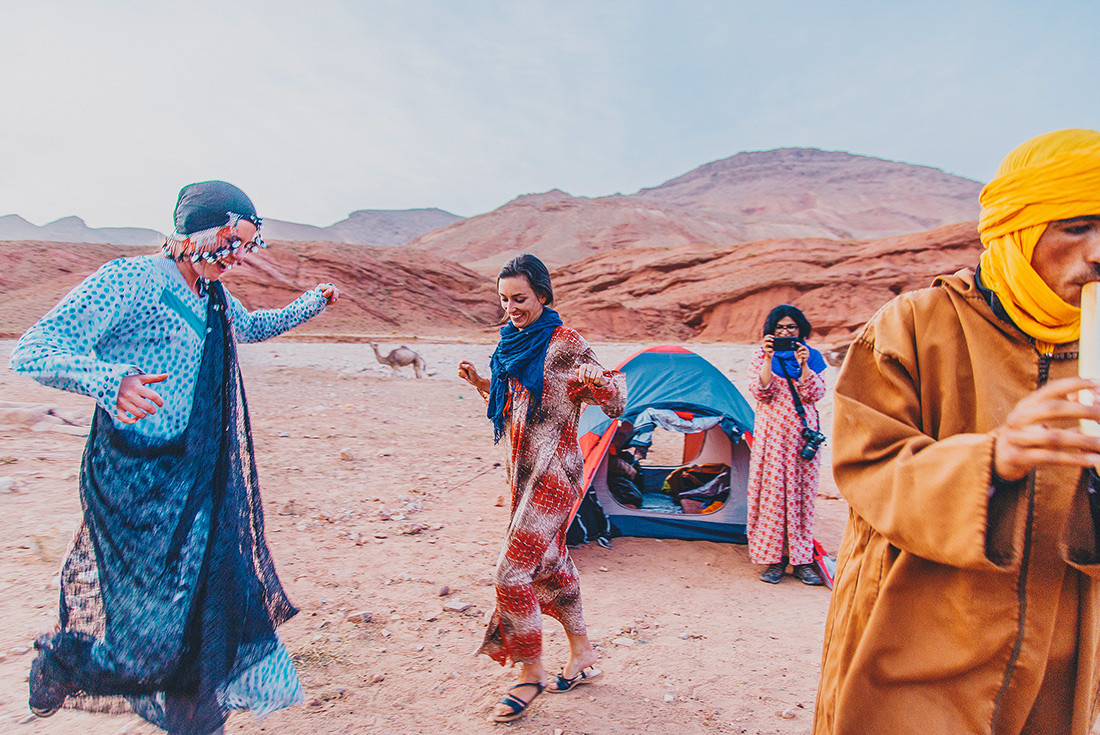 Intrepid travellers and local berber dancing at desert camp, Sahara, Morocco