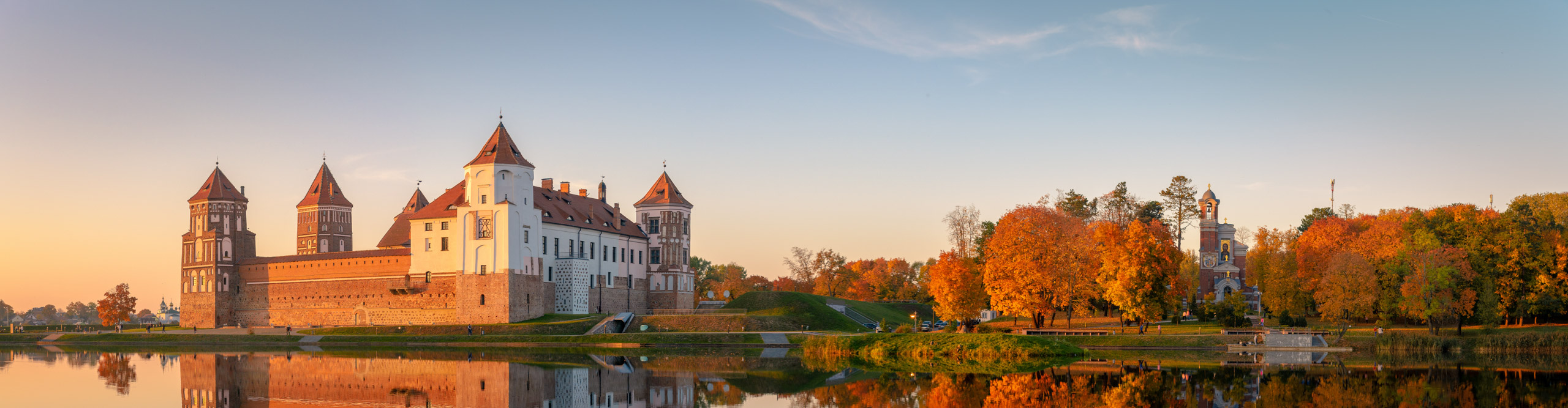 Mir castle in the warm glow of the setting sun, reflected in the water at Belarus