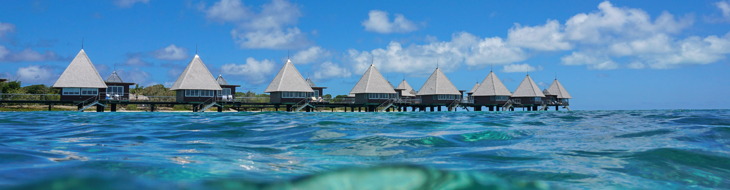 Overwater bungalows with clear blue water and blue skies, Caledonia