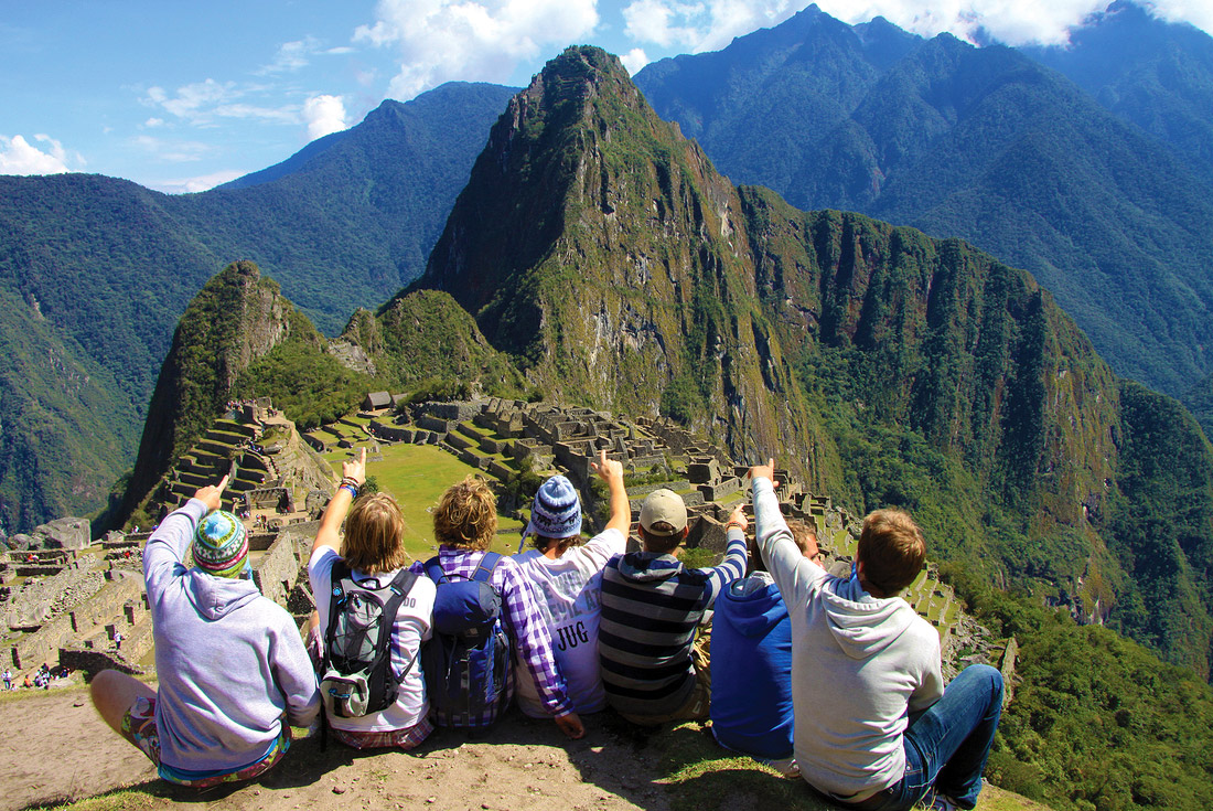 Group of travelling pointing towards view of Machu Picchu, Peru
