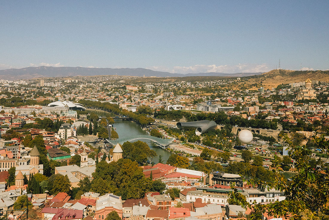 Panoramic view over Tbilisi, with a mix of modern and old architecture visible across the city