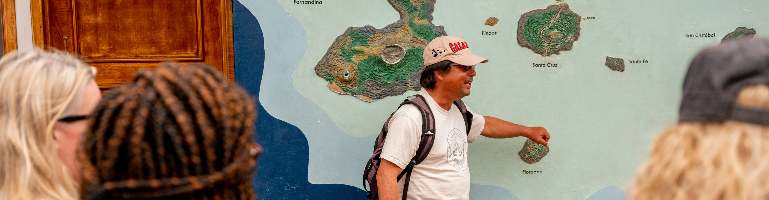 Guide talking in front of map of the Galapagos Islands, Ecuador