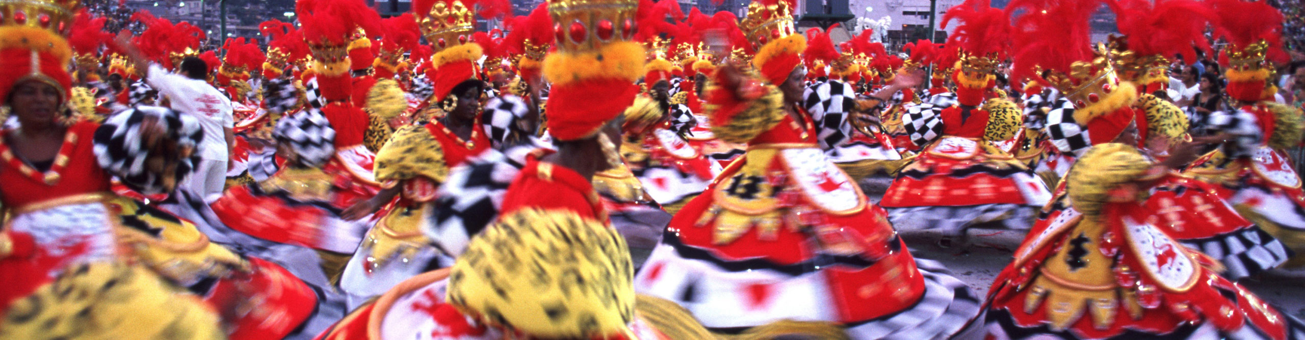 Woman dancing in colourful red and yellow costumes, with headdresses at the Rio carnival in Brazil 