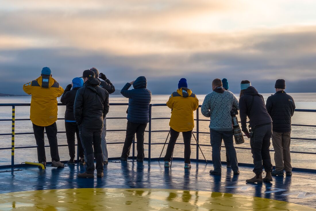 Passengers on the deck of the expedition vessel, looking out over Isabella Bay
