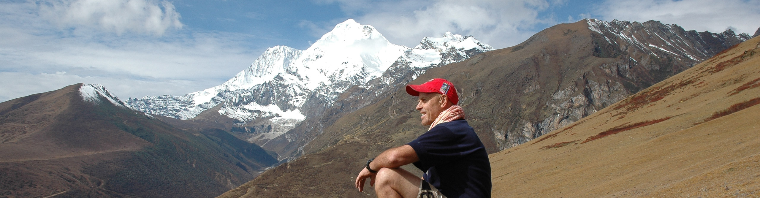 Man wearing a red cap looking at the view atop of the mountain in Bhutan on a clear sunny day