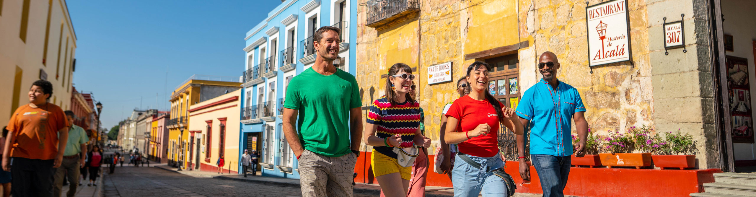 travellers walking down the street with colourful buildings in Mexico on a sunny day
