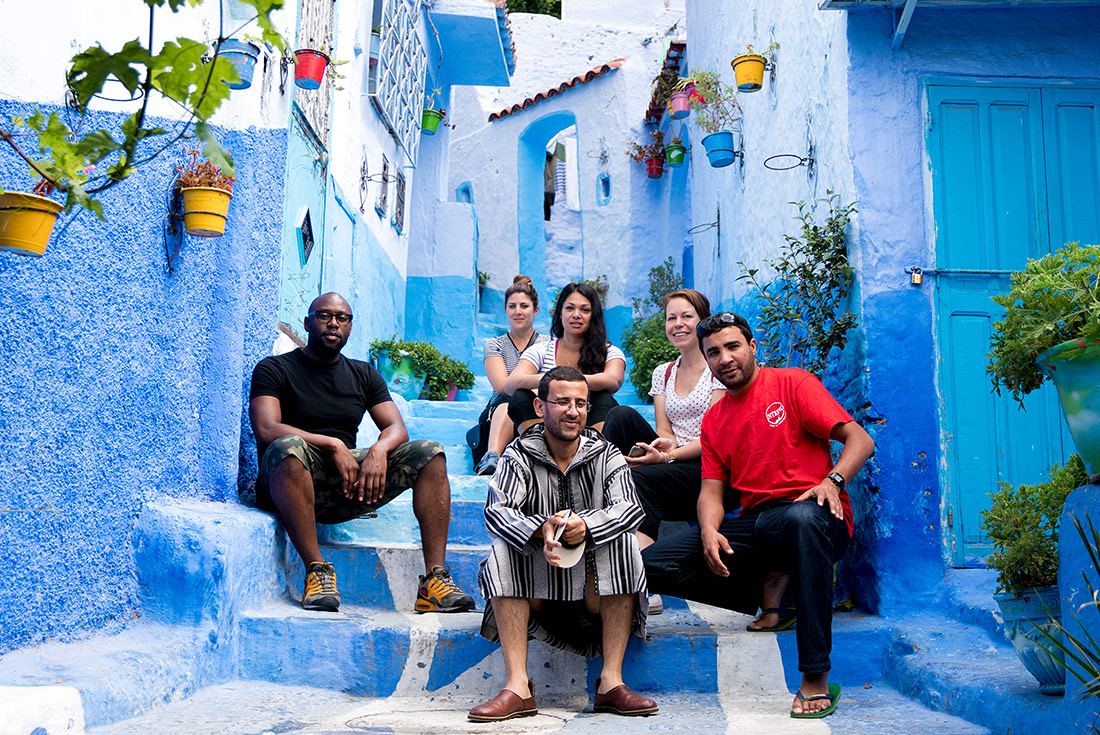 Intrepid Travel group sitting on stairs in blue streets of Chefchaouen, Morocco