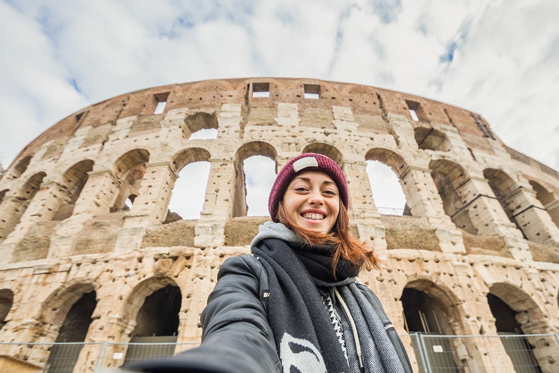 Traveller taking a selfing in front of the Colosseum in Rome, Italy.