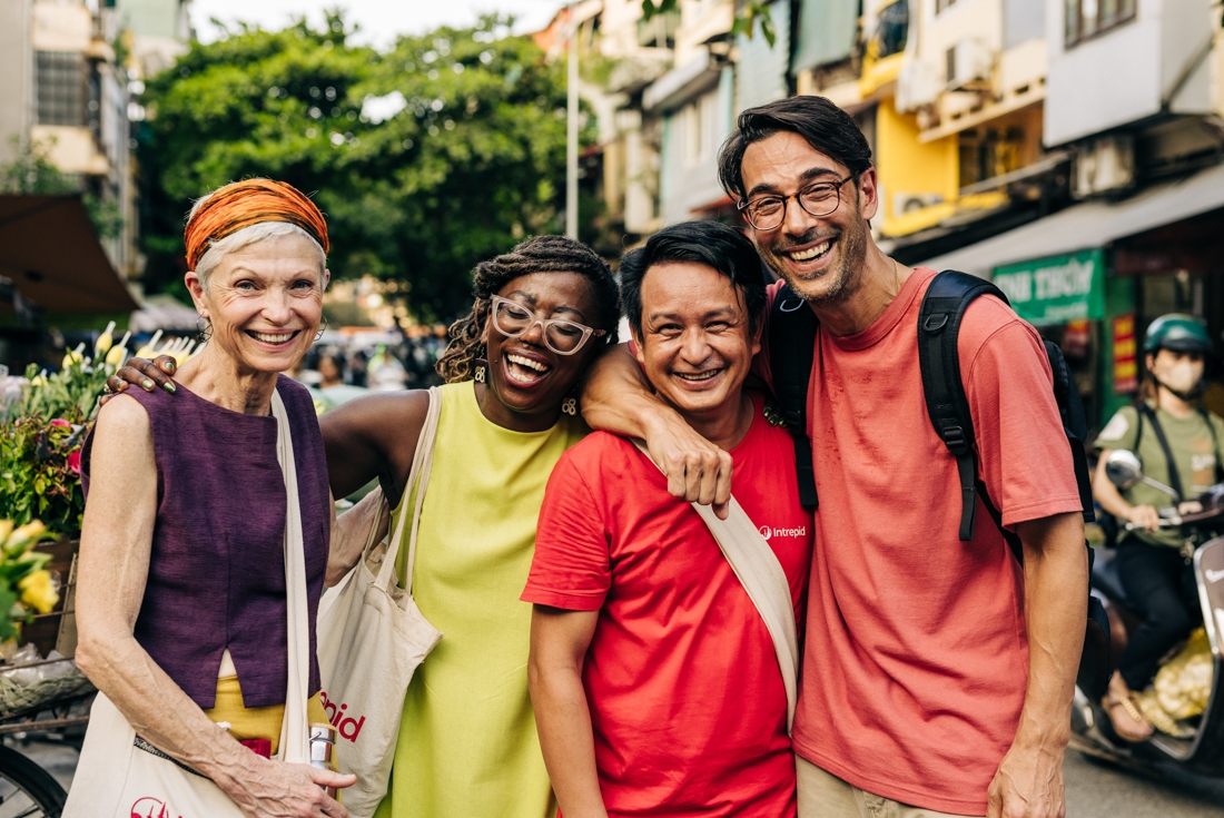 Intrepid travellers pose with leader with happy faces in the streets of Hanoi