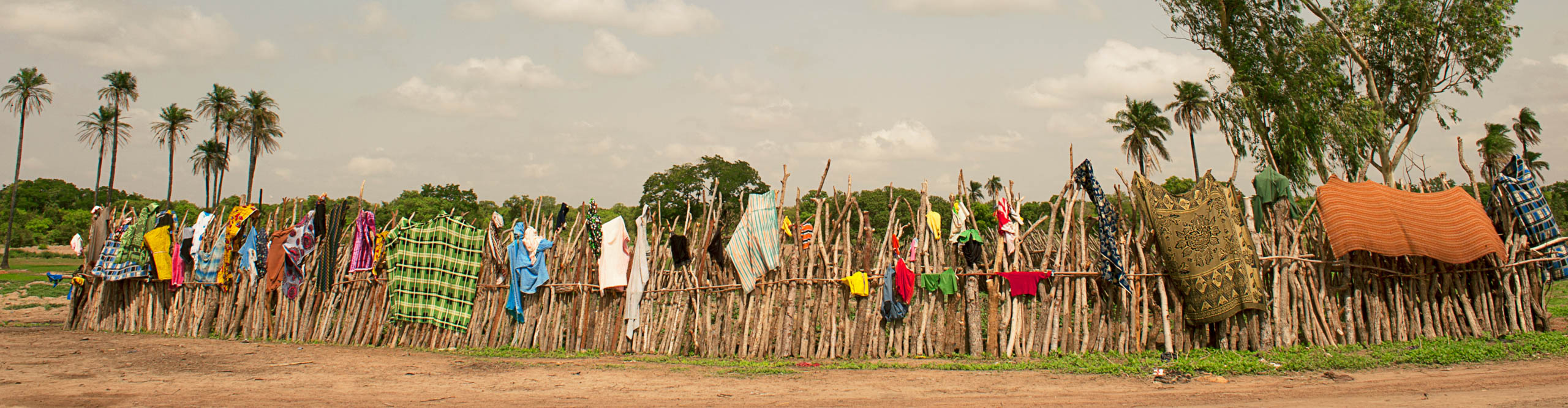 Colorful clothes hang on a wooden sticks, drying in the sun, in southern Burkina Faso.