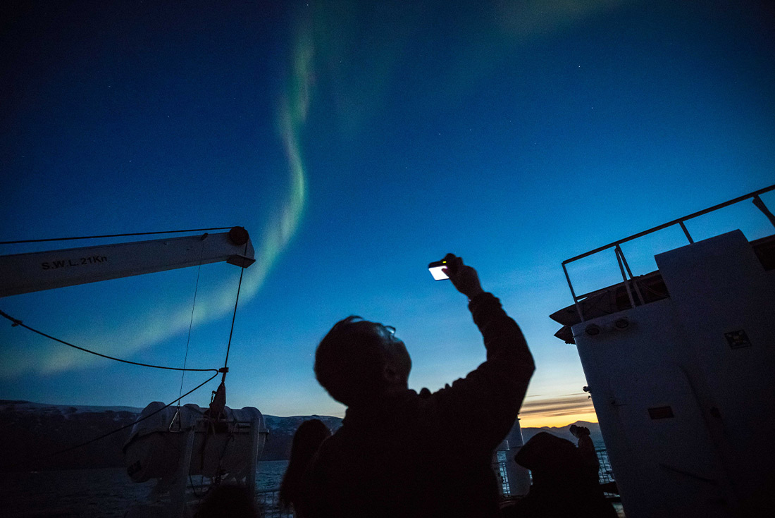 Traveller admiring the Northern Lights in Greenland