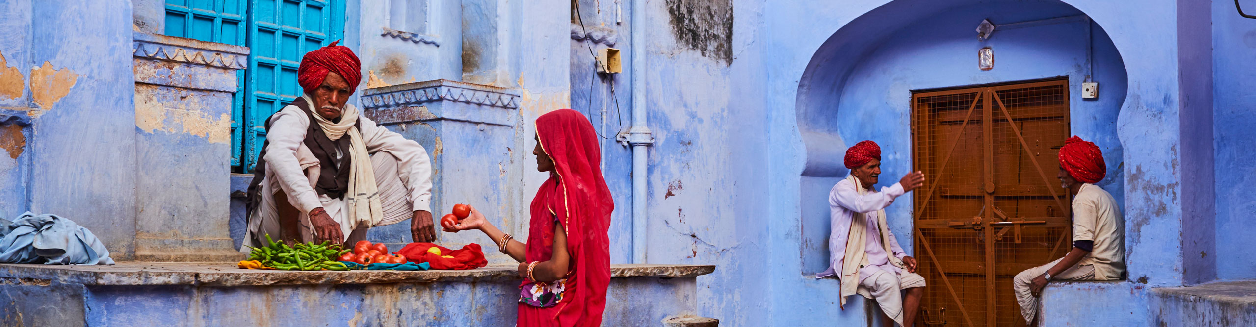 Man in turban selling vegetables to a woman in the blue city of Jodhpur, Rajasthan, India 
