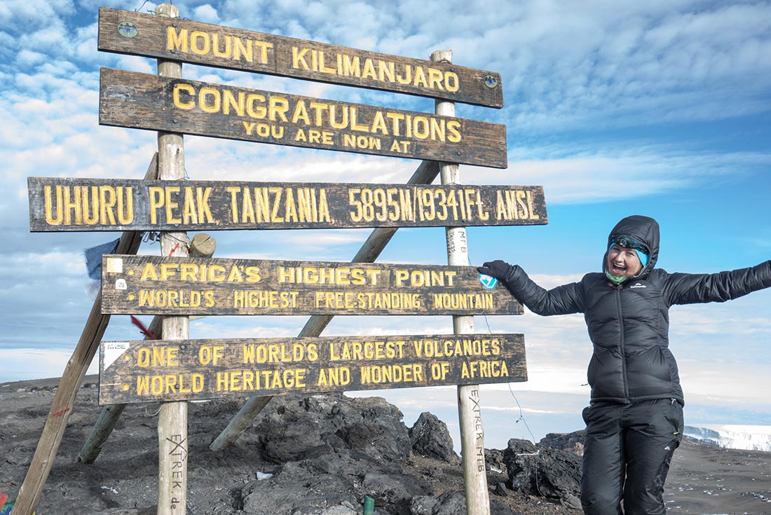 Intrepid traveller at Uhuru Peak summit sign, Mt Kilimanjaro, Tanzania