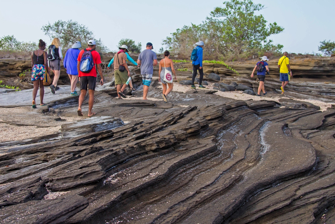 Group walking over volcanic lava formations, Galapagos Islands