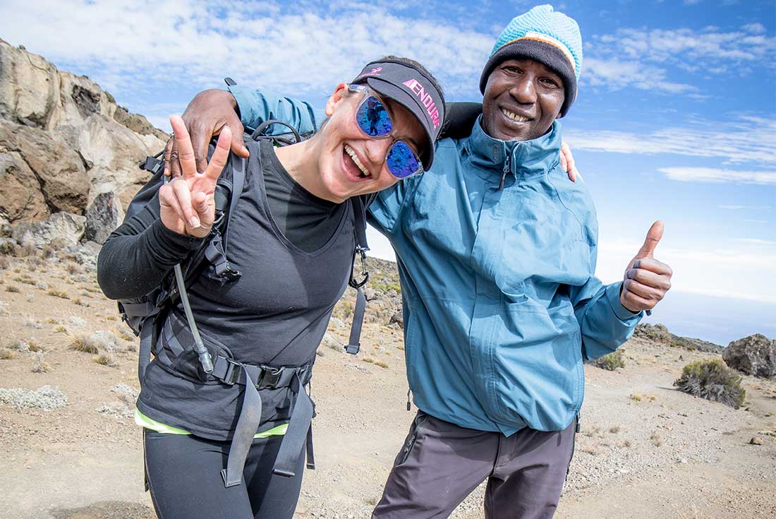 Hiker smiles with leader on the way to Mount Kilimanjaro 
