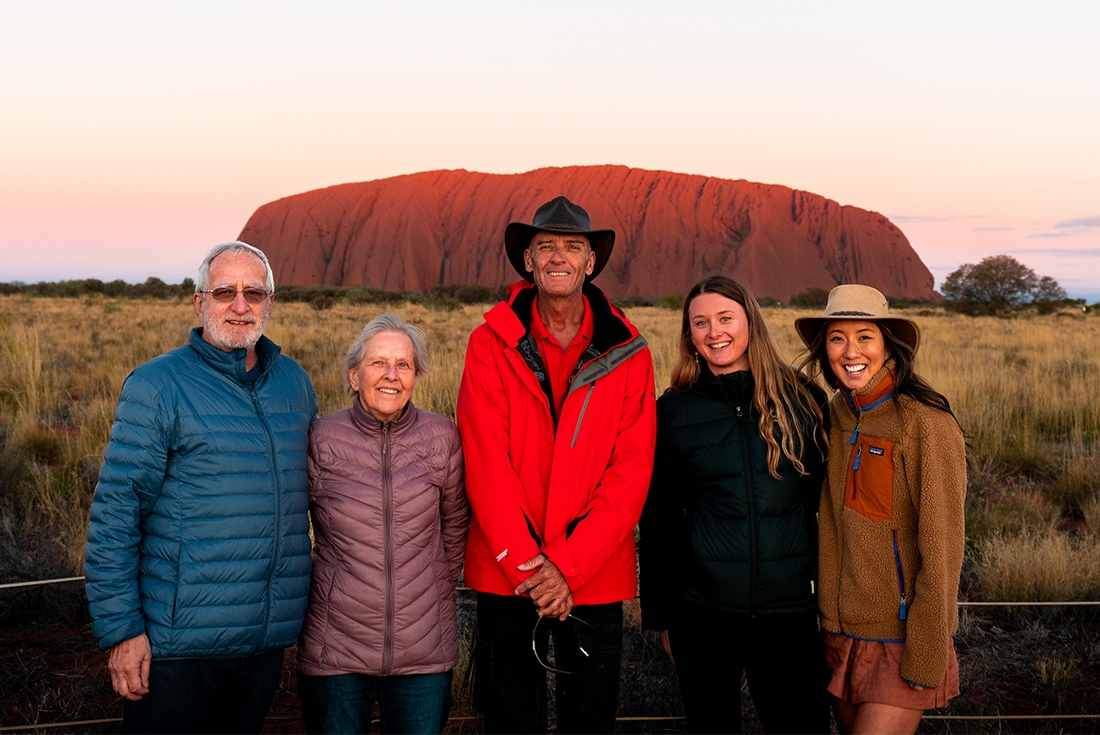 Leader and Travellers posing in front of Uluru at sunset