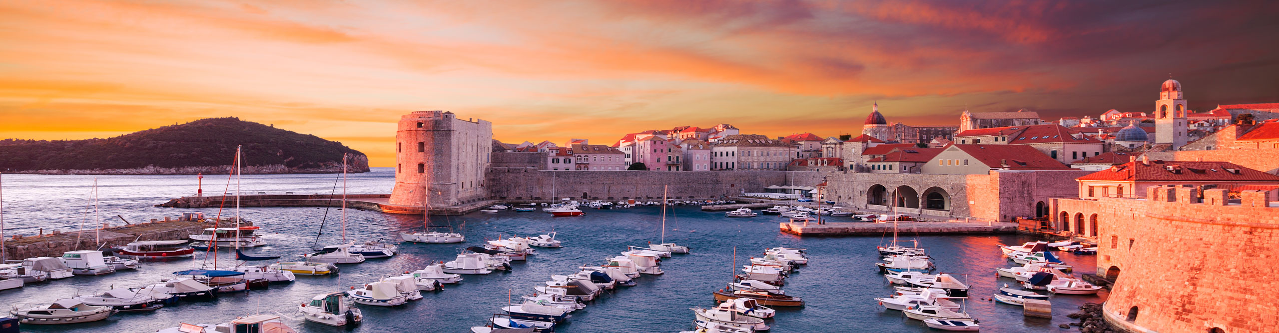 Dramatic sunset, with purple and orange clouds, over boats in the harbour, Dubrovnik, Croatia