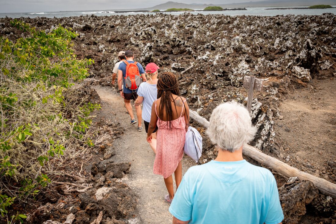 Passengers hike rocky terrain of Galapagos islands
