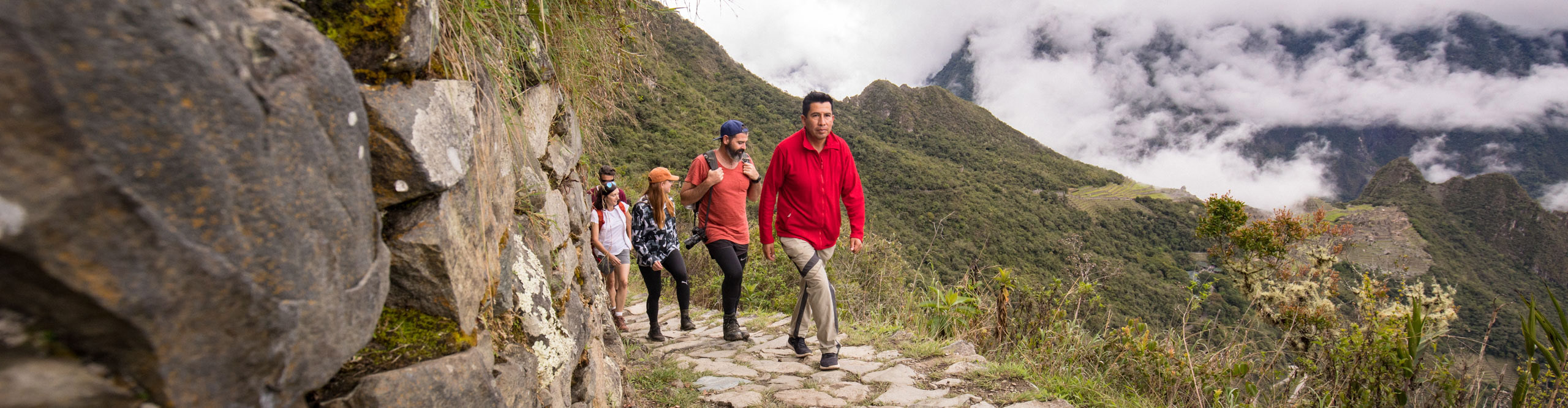Travellers hiking near Machu Picchu with clouds covering some of the valley, Peru