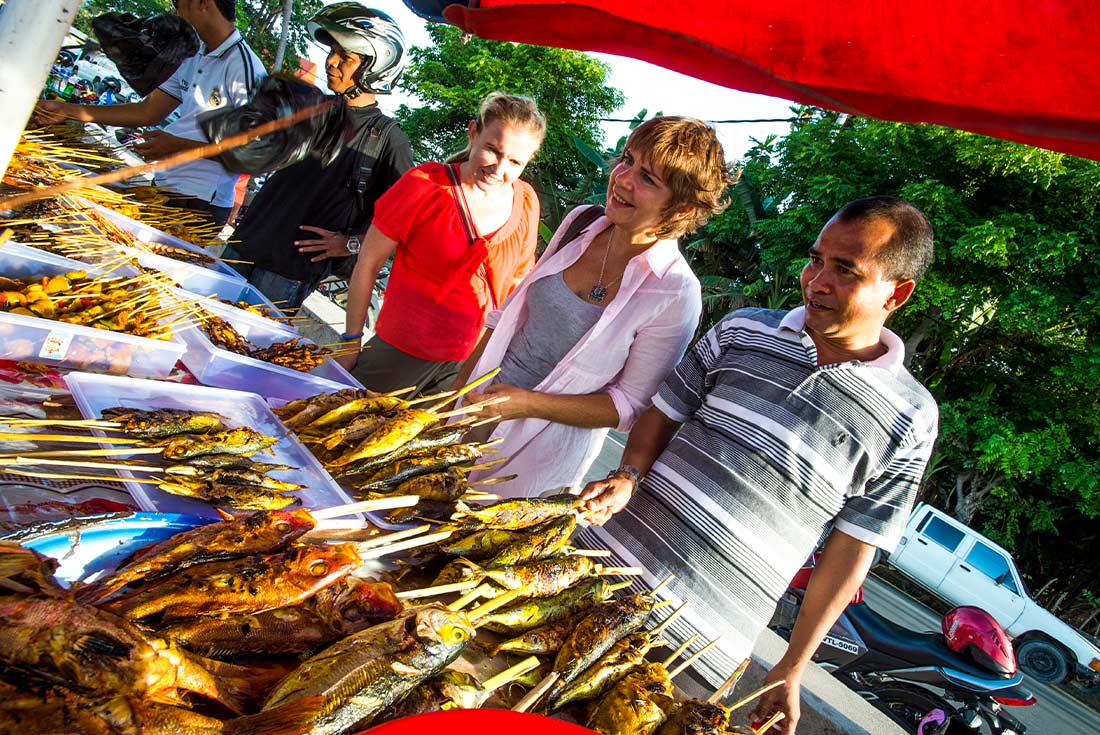 Travellers buy dried fish at market, Timor-Leste