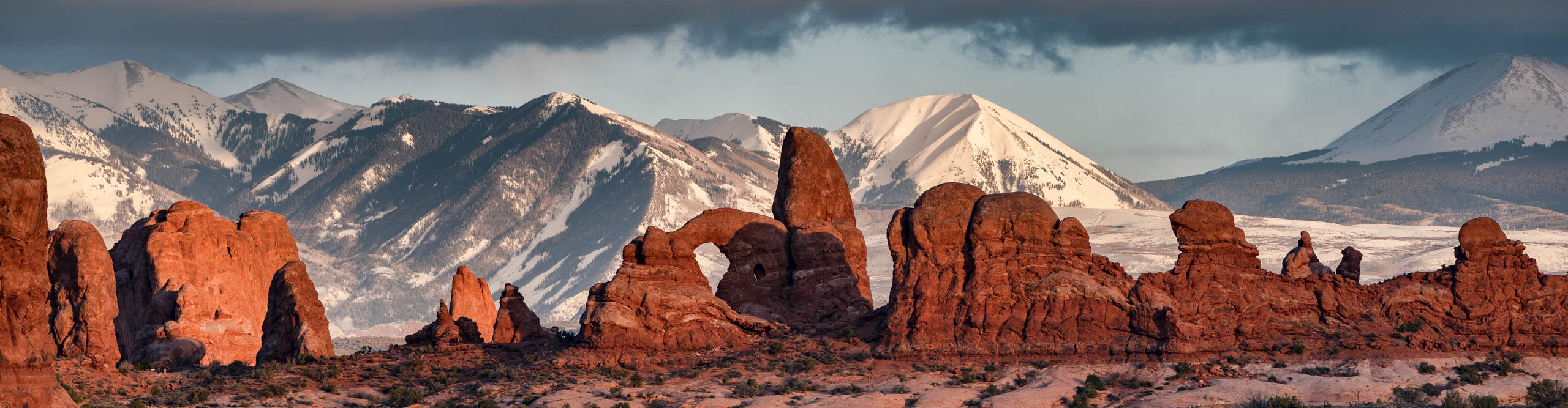 Turret Arch, Arches National Park with snow covered La Salle mountains in the background, at sunset 