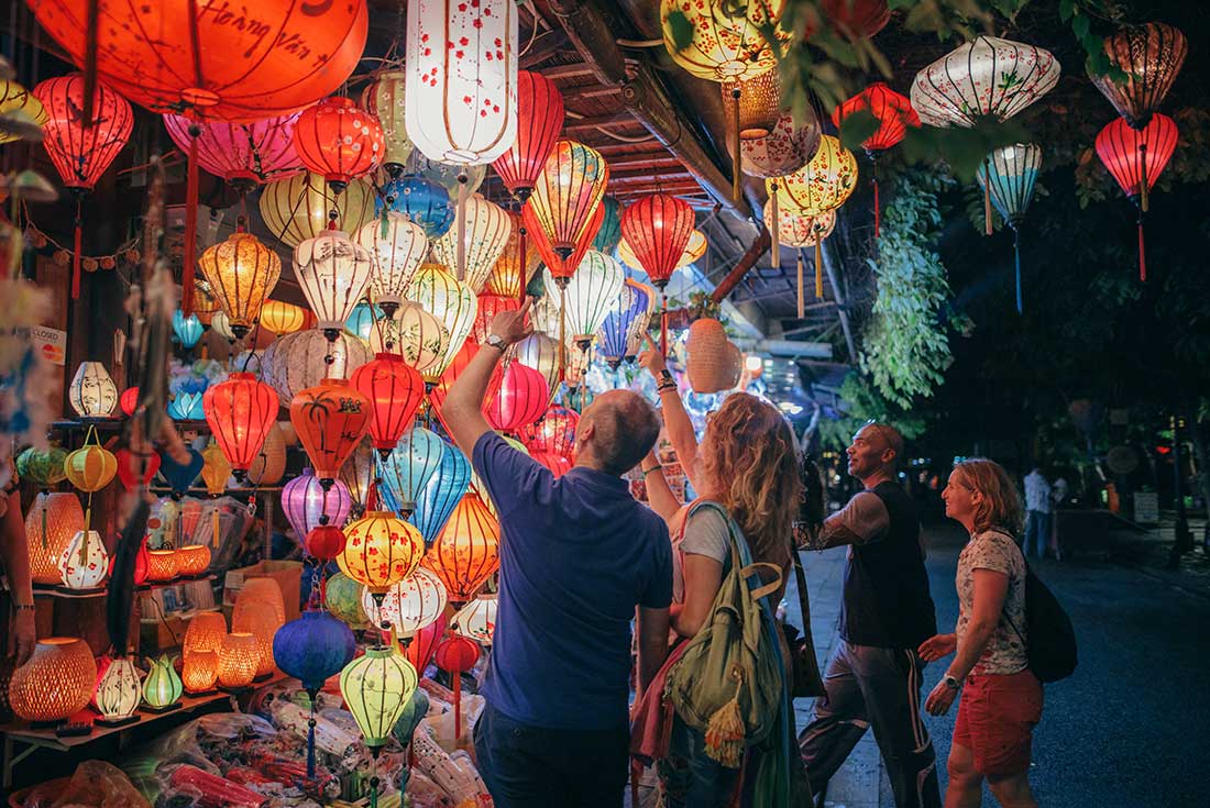 Travellers look at lanterns sold in local market in Hoi An