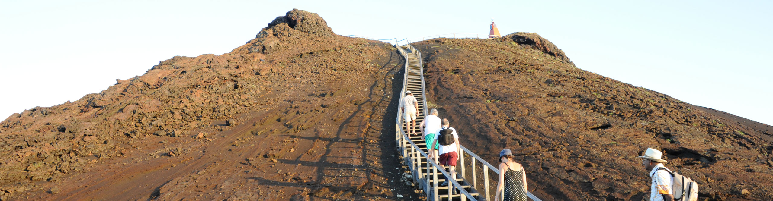 Group walking ups the stair on a hill in sunny weather on the Galapagos Islands 
