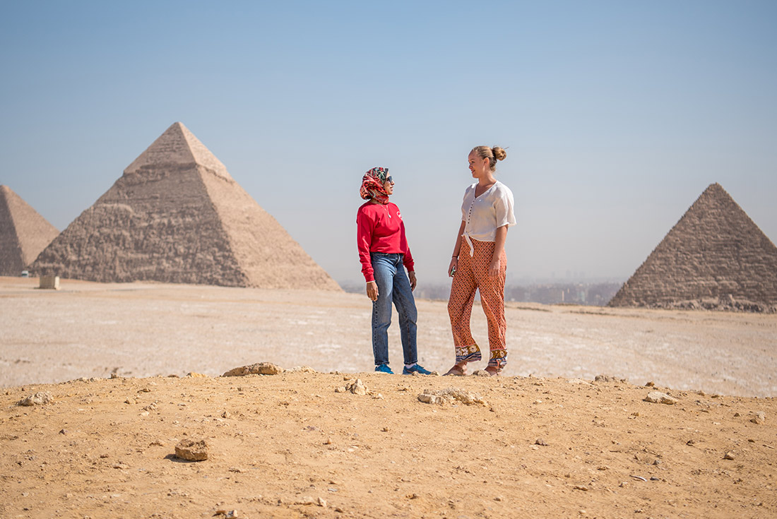 Leader and traveller talking in front of the Pyramids of Giza