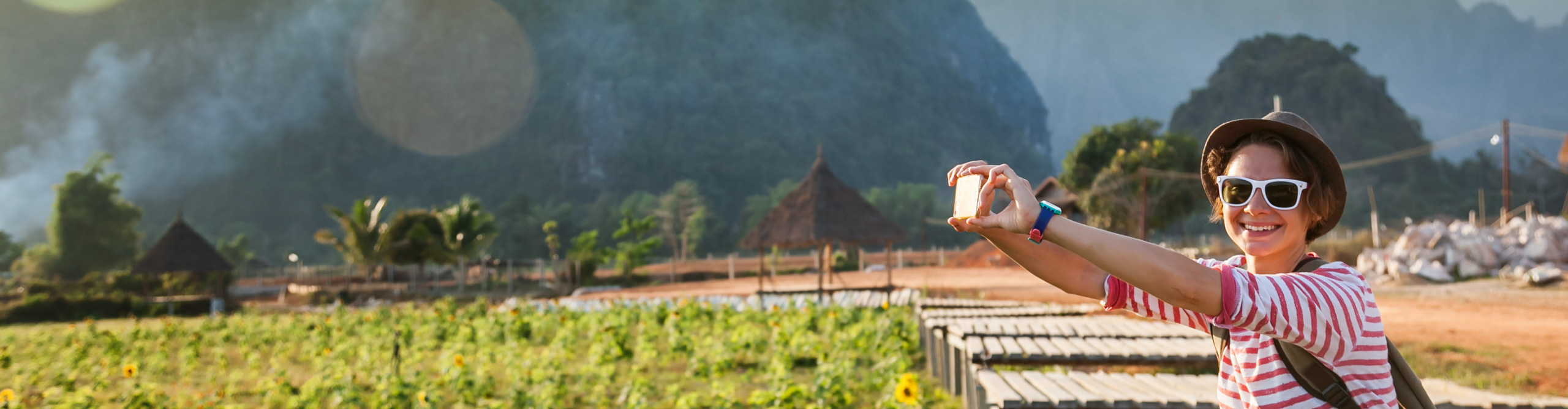 young woman photos on a mobile phone landscape in Laos, with mountains in the background 