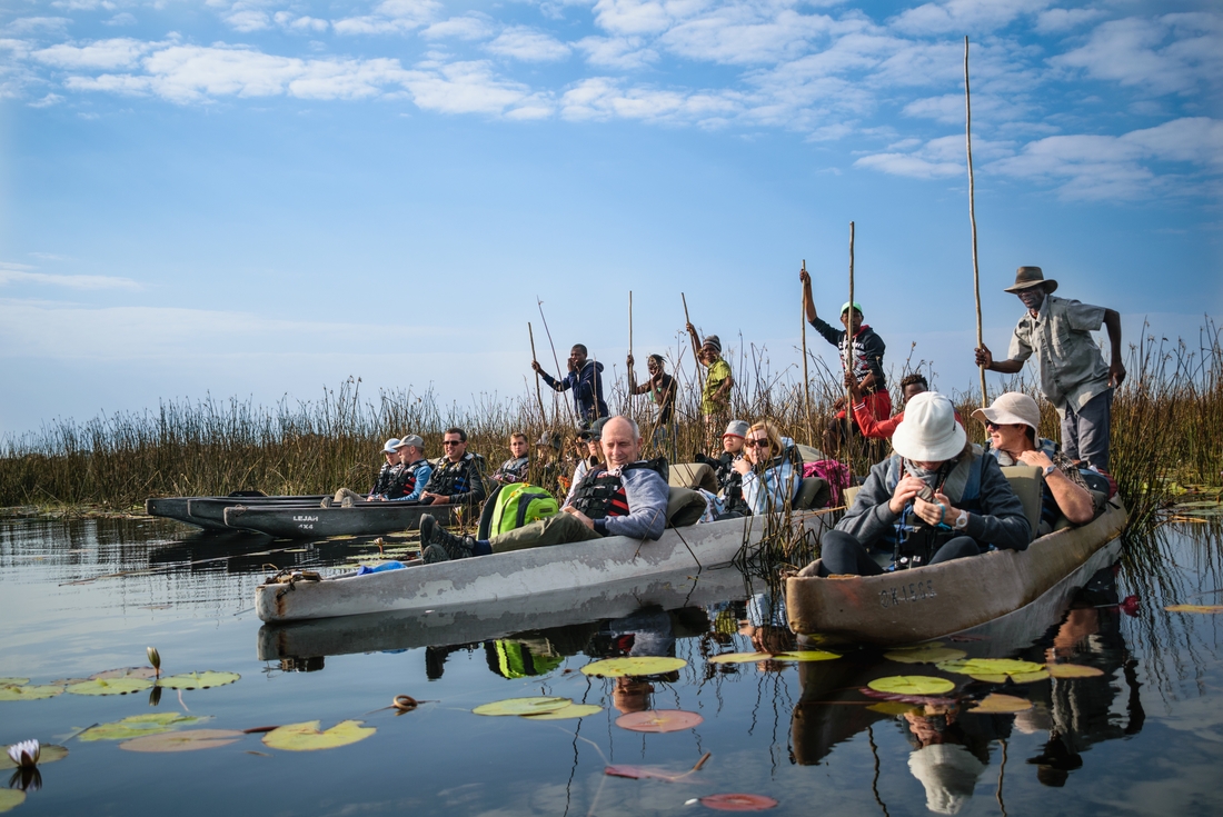 A group of travellers in the mokoro vessels (traditional canoes) with pole ... on the Okavango Delta in Botswana on an Intrepid Travel tour.