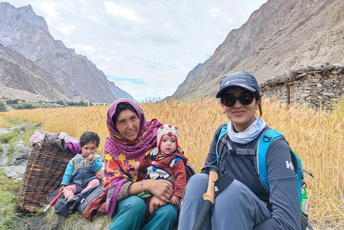 Traveller posing with local family with mountains in the background, Pakistan