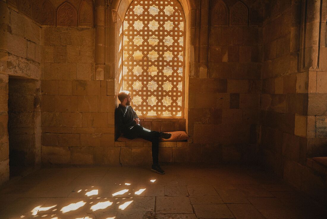 Intrepid traveller lounges in an intricately patterned window of the Shaki Khans Palace in Sheki, Azerbaijan