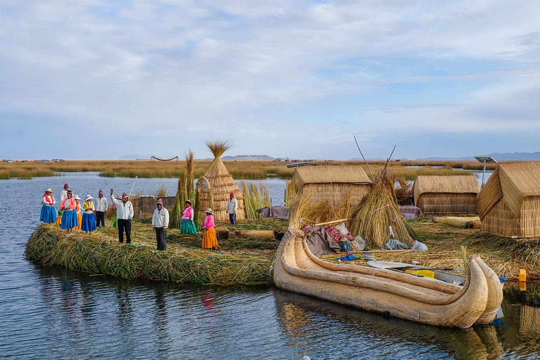 Locals waving welcome on floating island, Lake Titicaca, Peru