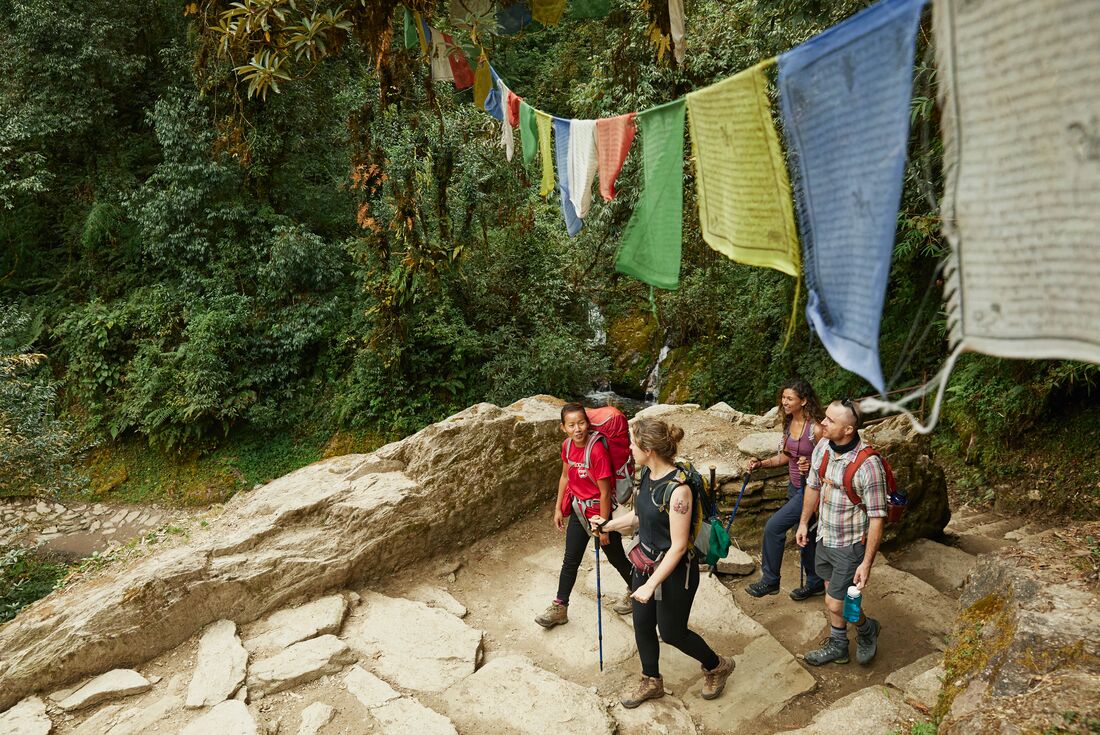 Travellers hike under prayer flags in Ghorepani, Nepal