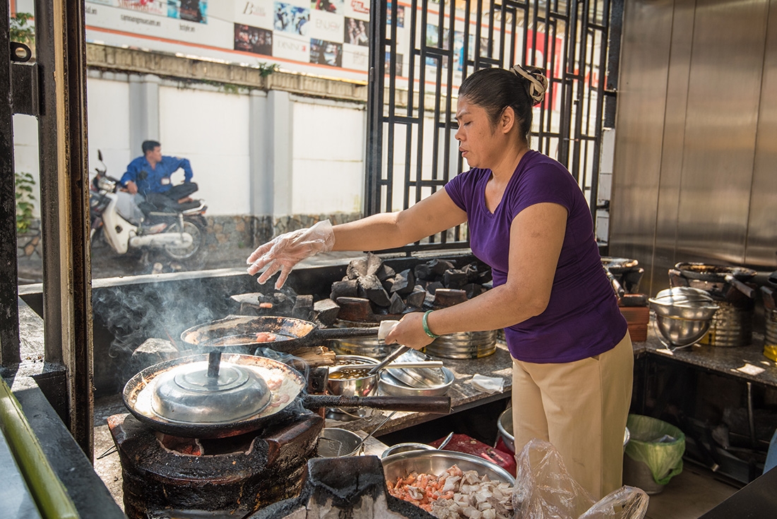 A local cook in a Ho Chi Minh City shopfront cooking a traditonal meal on an Intrepid Travel Tour
