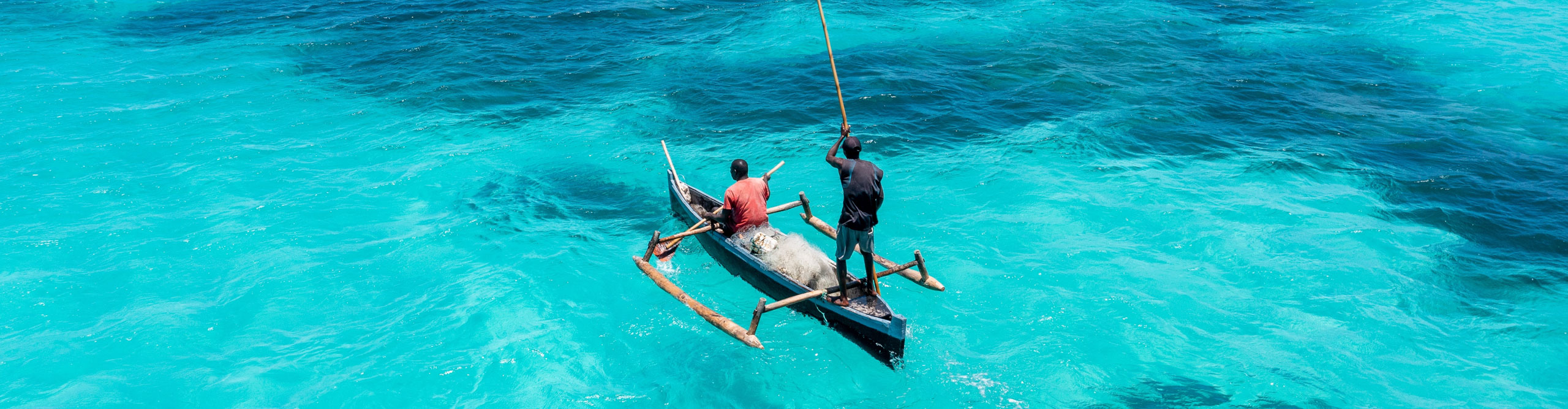 Fishermen in a boat in the coast of Mozambique, aerial drone view with tropical blue clear waters.