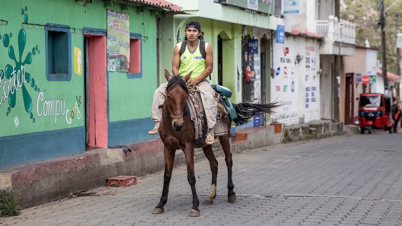 A man riding a horse through a Guatemalan city