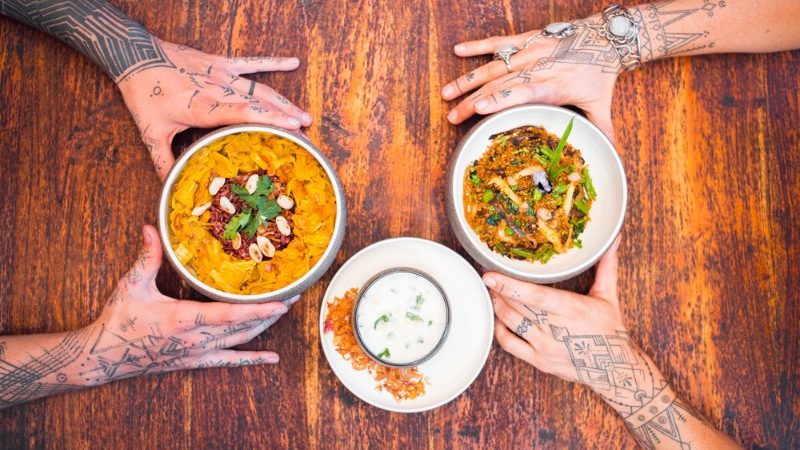 Hands around bowls of vegan food in Ubud