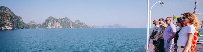 Passengers on board boat look out at the mountainous islands of Halong bay