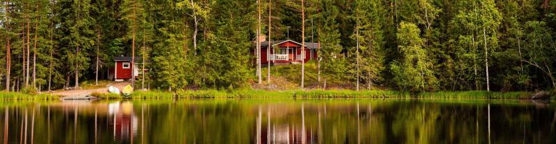 Red wooden cottages by the lake in rural Finland