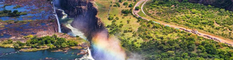 Rainbow forms on sunny day at victoria falls, zambia